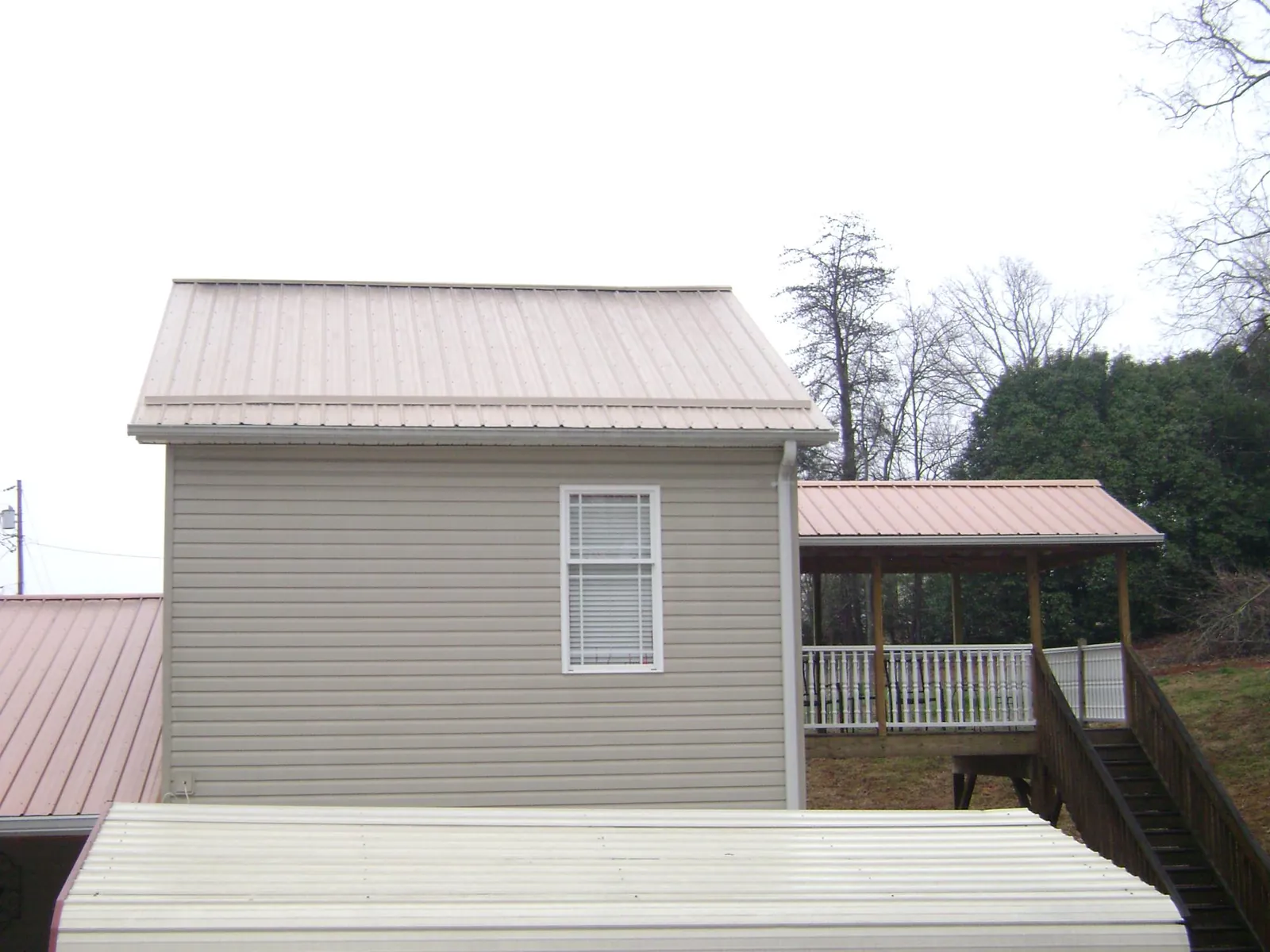 Tan metal roofs on a two story addition and attached porch, from a Roof Replacement job in Chesterfield